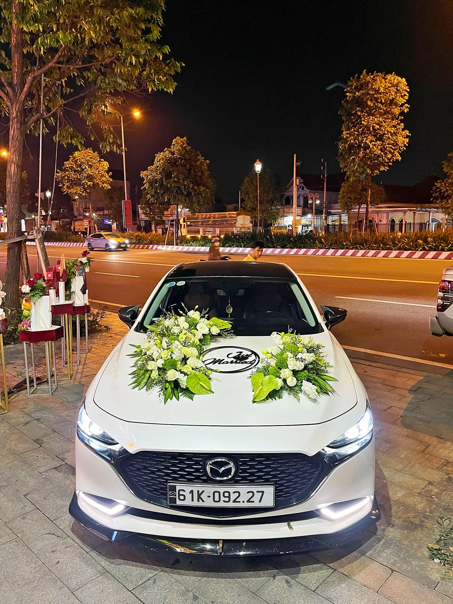 Xe trắng kết đôi cụm hoa trắng xanh với logo song hỷ – bộ Lục Bạch Song Hỷ
